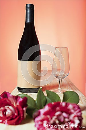 still life of bottle of red wine and a glass with roses with warm sunset background Stock Photo