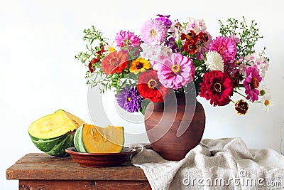 still life with a bouquet of flowers in a clay jug and pieces of pumpkin Stock Photo