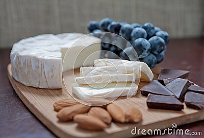 Still life of brie cheese, almonds, chocolate and grapes. Stock Photo