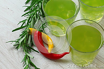 Still life with bright green cocktails on wooden background, chilli pepper and rosemary near Stock Photo