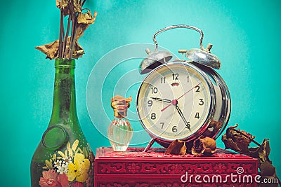 Still life with broken alarm clock, old glass vase with dead rose, perfume, vintage box Stock Photo