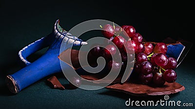 Still life, bunch of grapes with a broken bottle of wine on a dark background Stock Photo