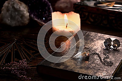 Still life with burning candle on old wooden table top, black fortune teller card, magic book and pentagram box Stock Photo