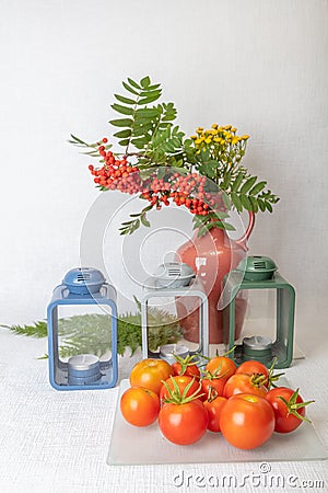 Still life, Candlesticks, vase with yellow flowers and rowan, fresh tomatoes.Concept, autumn harvest, vegetables without Stock Photo