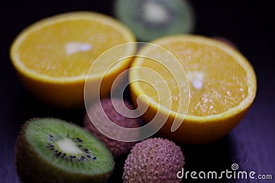 Still life of citrus, juicy kiwi and orange in the cut and Litchi chinensis on a dark background Stock Photo