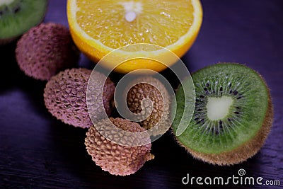 Still life of citrus, juicy kiwi and orange in the cut and Litchi chinensis on a dark background Stock Photo