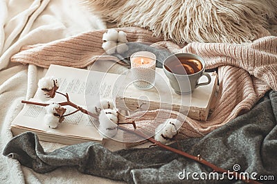 Still life in home interior of living room. Sweaters and cup of tea with a cone on the books. Read. Cozy autumn winter concept Stock Photo