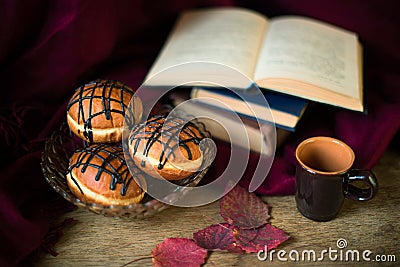Still life with donut berliner, cup for coffee, leaves and books Stock Photo