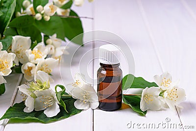 Still life of essential oil in a dark glass bottle and a flowering branch of jasmine Stock Photo