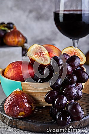Still life of grapes, peaches, figs and glasses of red wine on a gray Stock Photo