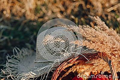 Still life with hat, bouquet, fruit in a basket in a field on hay. sunny summer weather Stock Photo