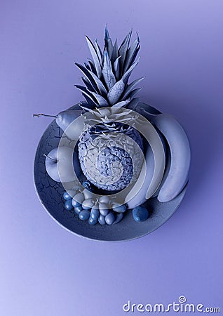 Still-life image of various fruits and a pineapple on a plate, with blue hues Stock Photo