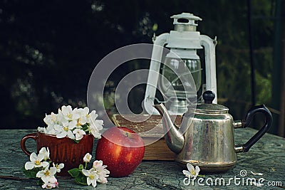 Still life with a lantern, an apple, a metal kettle and a large book on a green marble table, soon to school Stock Photo
