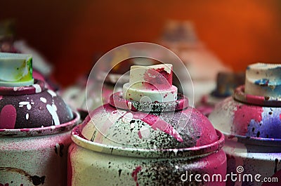 Still life with a large number of used colorful spray cans of aerosol paint lying on the treated wooden surface in the artist`s g Stock Photo