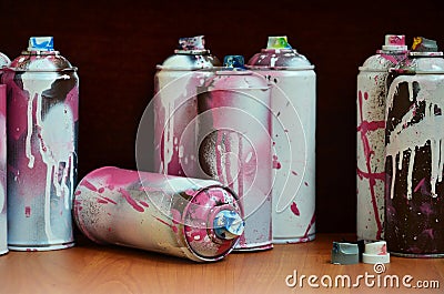 Still life with a large number of used colorful spray cans of aerosol paint lying on the treated wooden surface in the artist`s Stock Photo