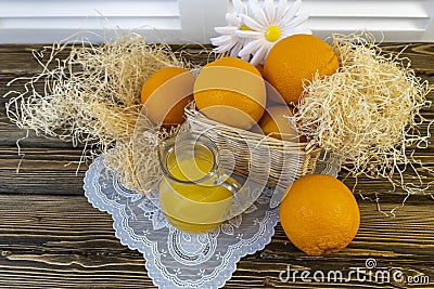 Still life with oranges, basket and glass jug with juice on old wooden background Stock Photo