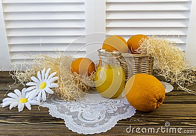 Still life with oranges, basket and glass jug with juice on old wooden background Stock Photo