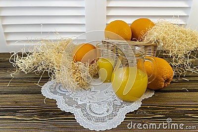 Still life with oranges, basket and glass jug with juice on old wooden background Stock Photo