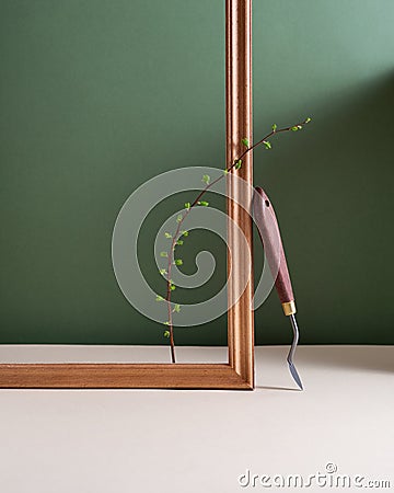 Still life photo. Minimalism still life with a palette knife, green branch and wooden frame. Art supplies Stock Photo