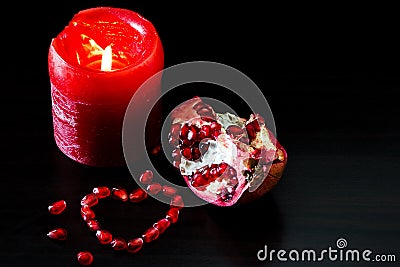 Still life with red candle and pomegranate heart. Concept romantic card. Stock Photo