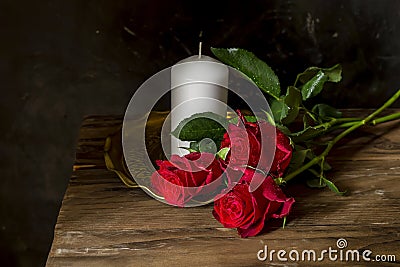 Still life with red roses and white candle close-up Stock Photo