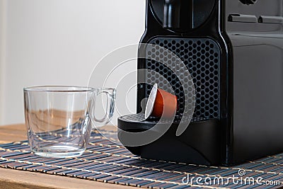 Still life of refreshing espresso capsule and cup next to coffee machine indoor at home. Nobody Stock Photo