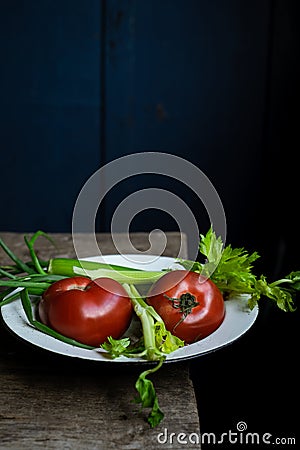 Still life with ripe tomatoes, celery, scallions on old wooden table Stock Photo