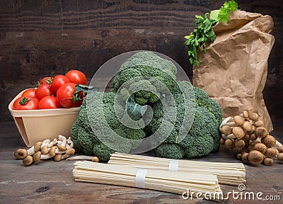 Still life vegetables cabbage broccoli with tomatoes mushrooms spaghetti green leaves wooden background Stock Photo