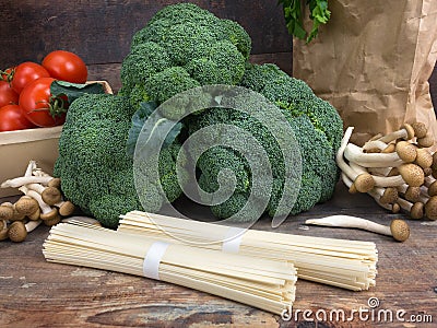 Still life vegetables cabbage broccoli with tomatoes mushrooms spaghetti green leaves wooden background Stock Photo