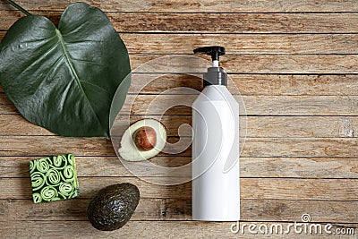 Spa composition with dispenser bottle, avocado fruit, soap and leaf on wooden surface top view Stock Photo