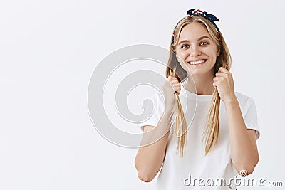 She is still little girl in heart. Charming cute fair-haired woman in headband, pulling hair down with both hands and Stock Photo