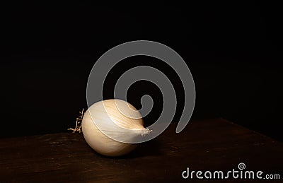 Stillife of an onion on a wooden table against a dark background Stock Photo