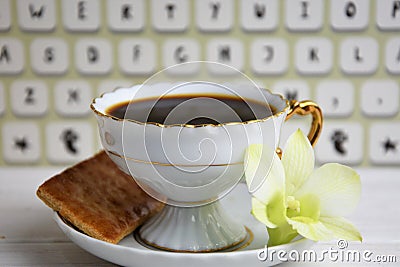 Stilllife of coffee cup with espresso, croissant or biscuit, flower and imitation of keyboard on a wooden background Stock Photo