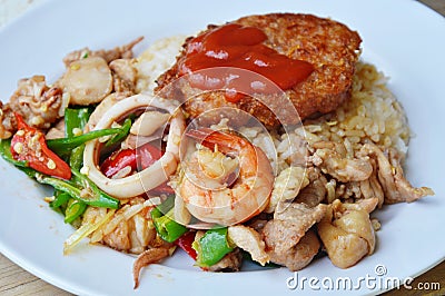 Stir fried mixed seafood with sweet long chili and deep fried pork on rice Stock Photo