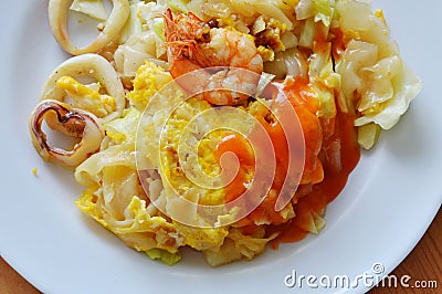 Stir fried rice noodle seafood and egg with cabbage dressing chili on plate Stock Photo