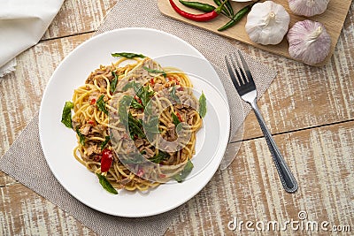 Stir fried Spaghetti with Canned tuna fish and crispy basil leaves in white plate,Spicy pasta Pad Kra Pao.Thai fusion food Stock Photo