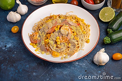 Stir fry with shrimp and pasta. On a blue texture with ingredients Stock Photo