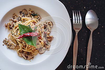 Stir fry Spaghetti with salted fish, Thai spices and dry chili, in white dish, with fork and spoon Stock Photo