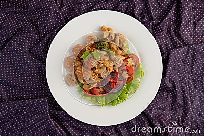 Stir shrimp macaroni on a white plate with tomatoes and salad Stock Photo