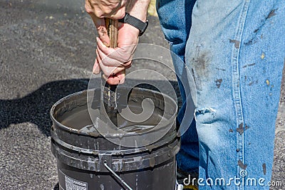 Stirring Asphalt sealer before use Stock Photo