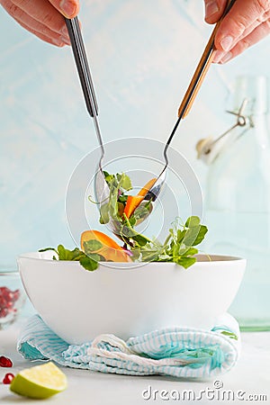 Stirring a bright persimmon salad. Healthy green vegetarian food Stock Photo