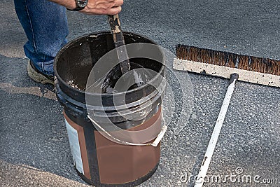 Stirring can of asphalt before pouring on driveway Stock Photo