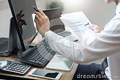 Stock exchange trader Analyzing Graphs chart or data On Multiple Screens in office Stock Photo