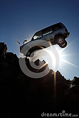 silhouette of a generic car crashing flying off a cliff. Stone cliff. Blue sky. sun rays. Car accident. Stock Photo