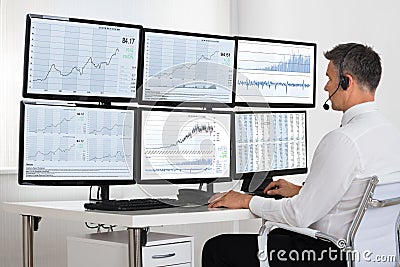 Stock Market Broker Looking At Graphs On Multiple Screens Stock Photo