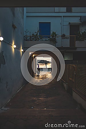 Cozy alleyway at sunset in Italy with illuminated lamps and parked scooter Stock Photo