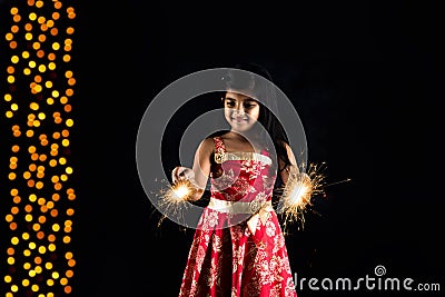 Stock photo of indian little girl holding fulzadi or sparkle or fire cracker on diwali night Stock Photo