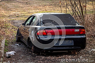 Stolen car left robbed without wheels and with broken windows ina forest Stock Photo
