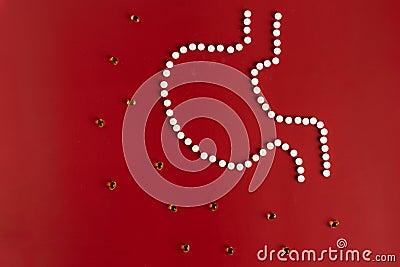 The stomach is laid out of tablets on a maroon background along with yellow drops of vitamins Stock Photo