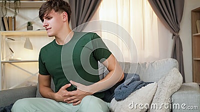 Stomach pain man grasping belly sitting sofa home Stock Photo